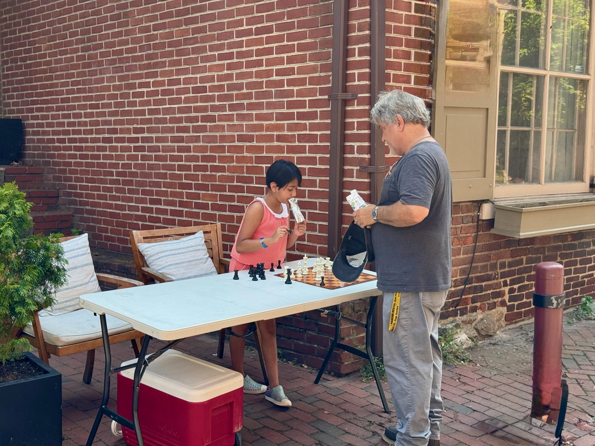 Tanya playing a game of chess with a visitor at her lemonade stand on Elfreth's Alley